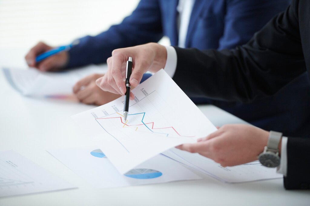 Two advisors reviewing printed financial charts and graphs across a desk