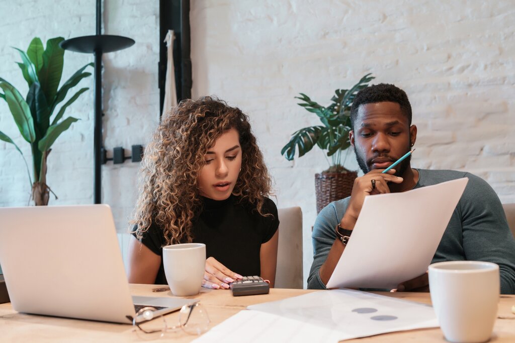 Two colleagues reviewing financial documents and a laptop at a table